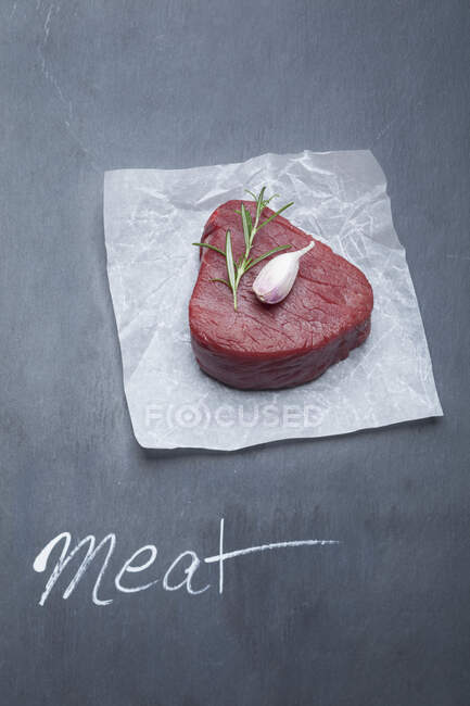 Beef tenderloin with garlic and rosemary on parchment — Stock Photo
