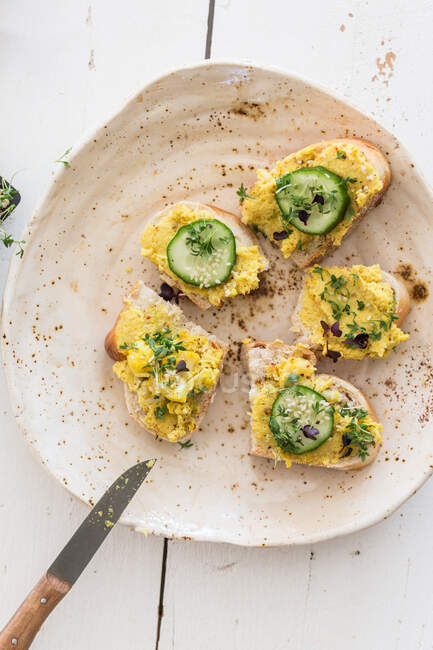Open sandwiches topped with a turmeric spread, cucumber slices and cress — Stock Photo