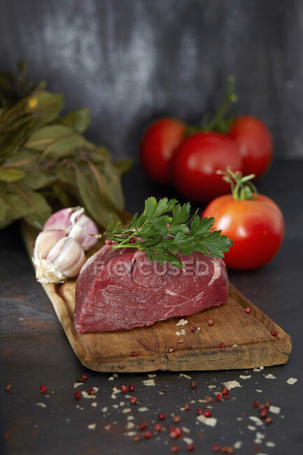 Un filete de carne cruda en una tabla de madera - foto de stock