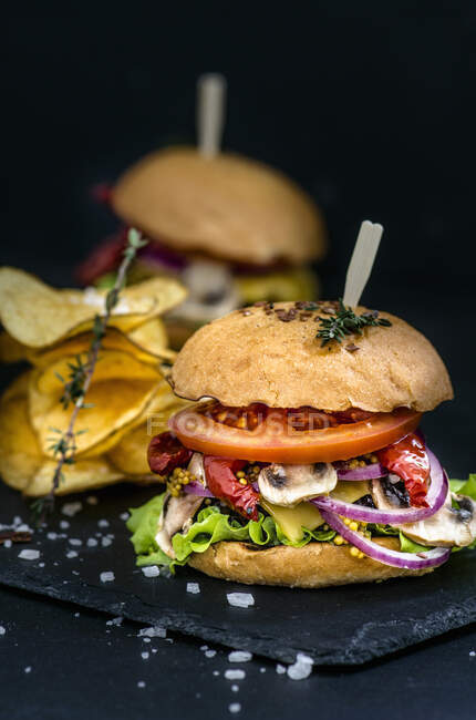 Burger und Kartoffelchips auf schwarzem Hintergrund — Stockfoto