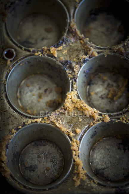 An empty muffin tins with cake crumbs — Stock Photo