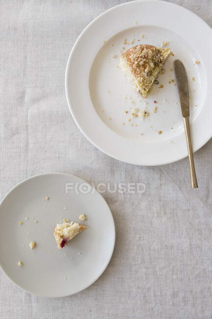 Une assiette blanche avec un morceau de gâteau et une assiette avec un morceau de gâteau avec des miettes — Photo de stock
