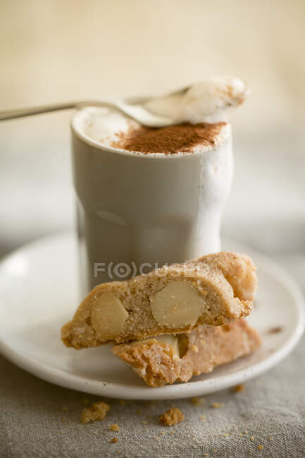 Plate of macadamia cantucci with cappuccino in cup — Photo de stock