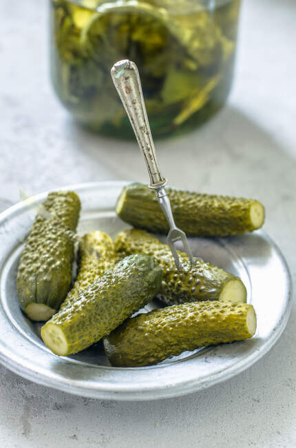 A plate of gherkins in front of a gherkin jar — Stock Photo
