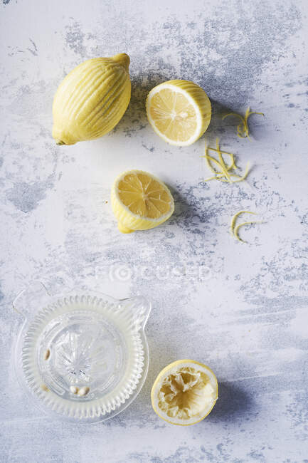 Limones pelados y exprimidor, fondo claro - foto de stock
