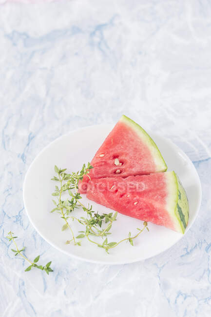 Watermelon wedges and fresh thyme on plate — Stock Photo