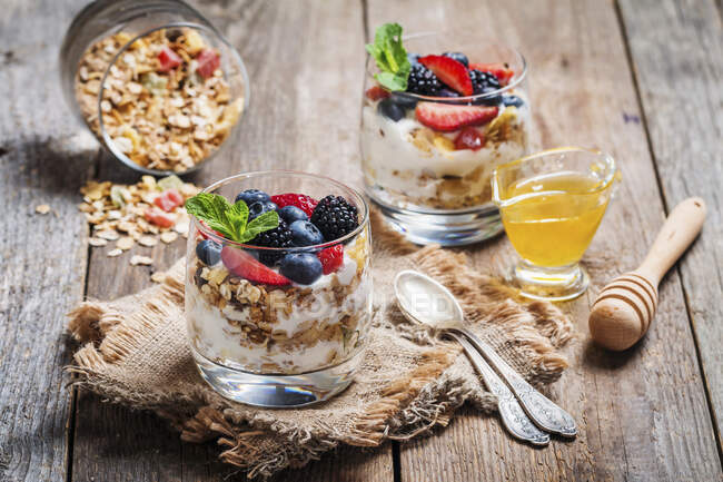 Homemade yogurt with baked granola and berries in small glasses on wooden background — Stock Photo