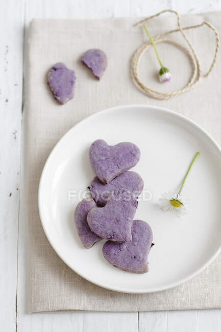 Фиолетовое печенье с цветами на тарелке — стоковое фото