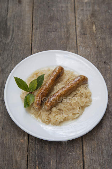 Salsicce di soia su crauti con alloro fresco su sfondo di legno — Foto stock