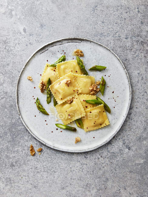 Goat's cheese ravioli with green asparagus, walnuts, chilli flakes and olive oil — Stock Photo