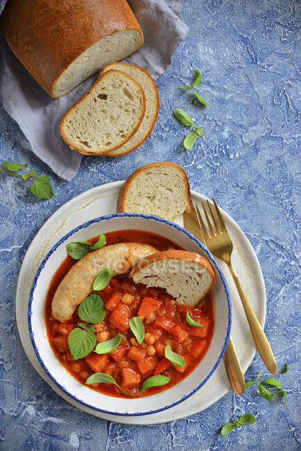Gulasch mit Kichererbsen und Wurst, Gemüse und Basilikumblättern serviert mit Brot — Stockfoto