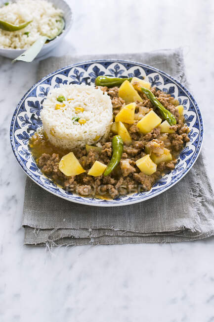 Plate with picadillo con papas garnished with green peppers and served with rice, sweet corn and peas — Stock Photo