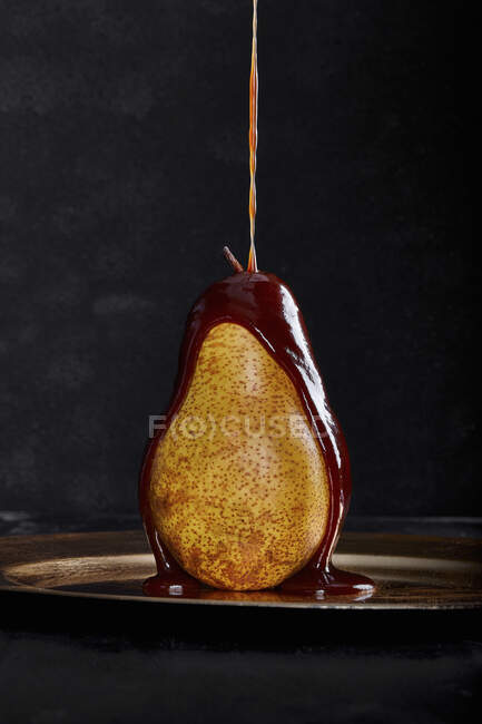 Chocolate vertiendo sobre una pera madura - foto de stock