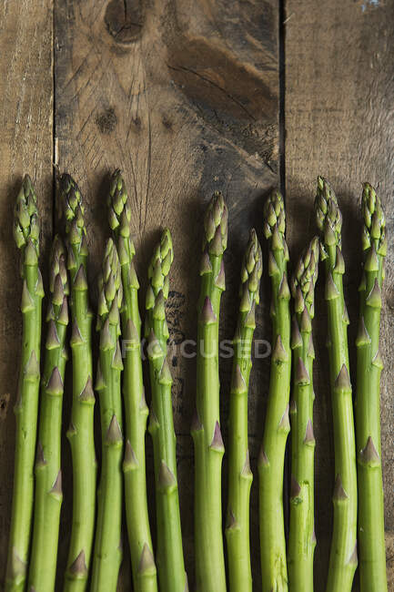 Lance di asparagi verdi su fondo di legno (vista dall'alto) — Foto stock