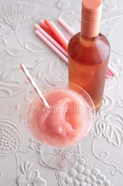 Un FRO granuloso in un bicchiere da cocktail con una bottiglia di vino rosato — Foto stock