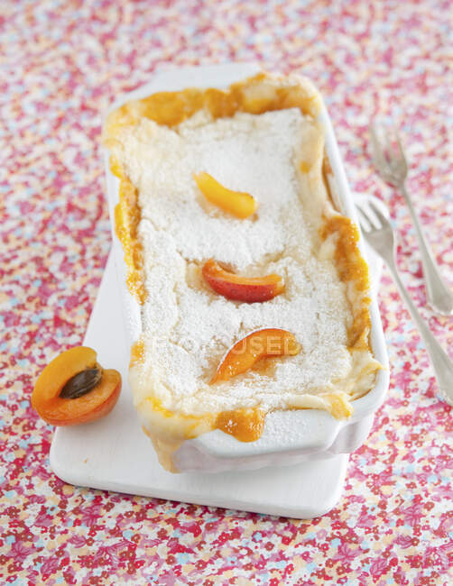Torta con albicocche in latta sul tavolo con tovaglia floreale stampata — Foto stock