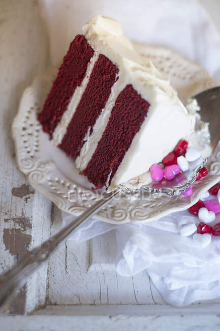 Un pedazo de pastel de terciopelo rojo y gotas de corazón - foto de stock