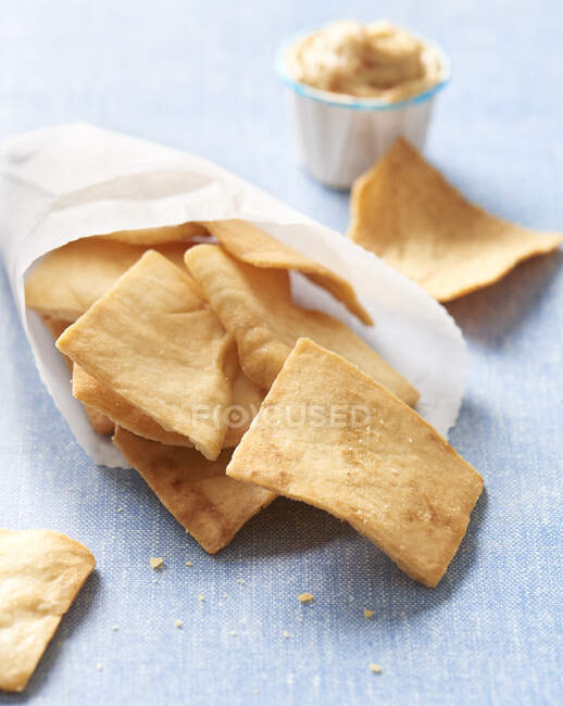 Chips de pita con hummus en superficie azul - foto de stock