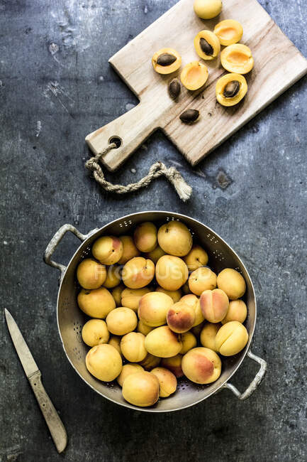 Fresh Apricots in metal colander and on wooden board — Stock Photo