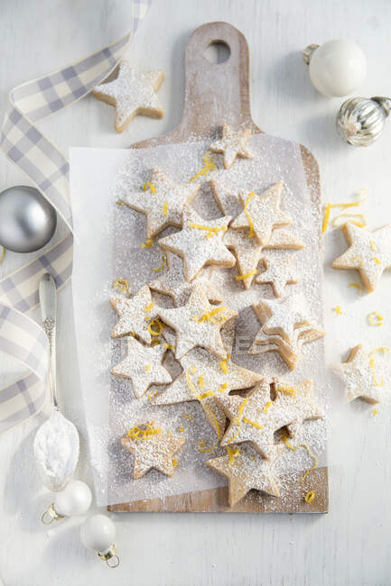 Lemon shortbread stars with powdered sugar on wooden board — Stock Photo
