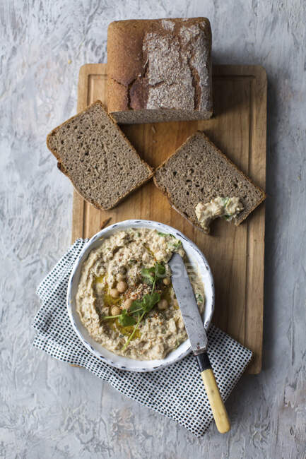 Rye bread with homemade hummus on wooden board — Stock Photo