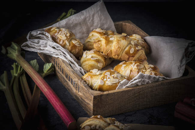 Rhubarb croissants on a linen cloth in a wooden crate — Stock Photo