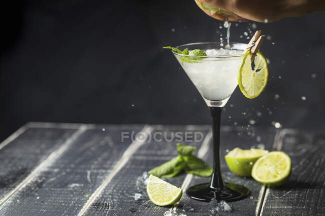 Hand squeezing lime in glass of margarita cocktail — Stock Photo