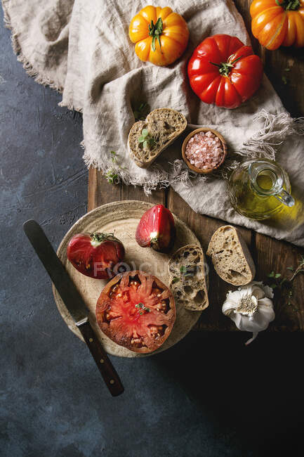 Tomates orgânicos vermelhos e amarelos com azeite, alho, sal e pão para salada ou bruschetta — Fotografia de Stock