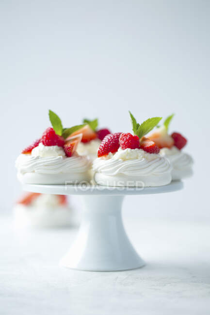 Pavlovas with whipped cream and berries on ceramic stand — Stock Photo