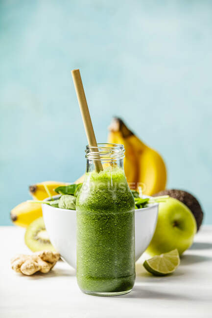 Green smoothie and ingredients on the table against the wall — Stock Photo