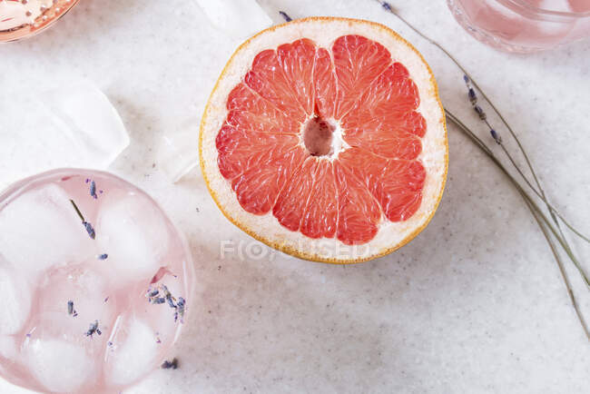 Halbierte Grapefruit, trockener Lavendel und Gläser Grapefruit, Gin und Lavendel Fizz mit Eiswürfeln — Stockfoto