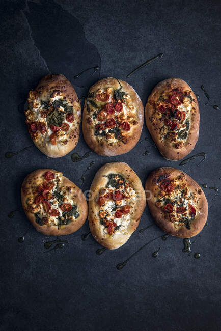 Individual flatbreads topped with feta cheese, spinach and tomatoes — Stock Photo