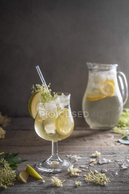 Elderflower cordial cocktail with lemon and apple slices on ice — Stock Photo