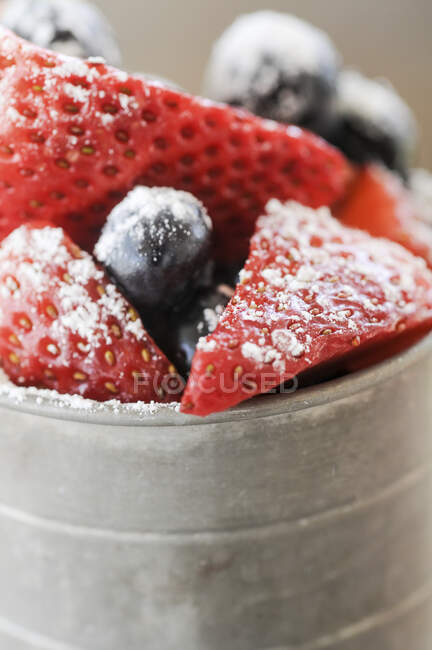 Cut strawberries and blueberries with powdered sugar — Stock Photo