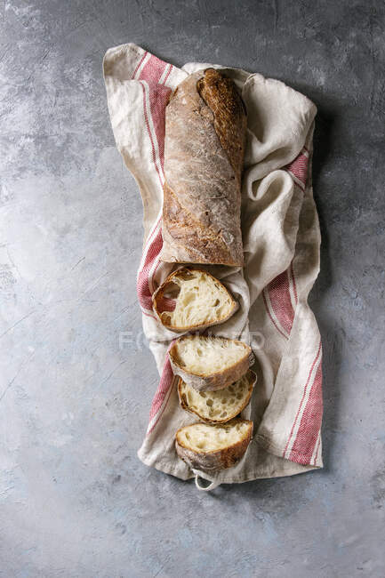 Affettato fresco al forno artigianale pane ciabatta integrale su asciugamano da cucina su sfondo texture grigia — Foto stock