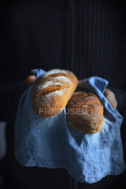 A man holds a baguette in his hands — Stock Photo