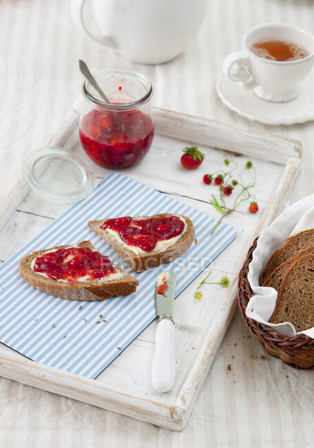 Pan con mantequilla y mermelada de fresas silvestres en pan y en frasco - foto de stock