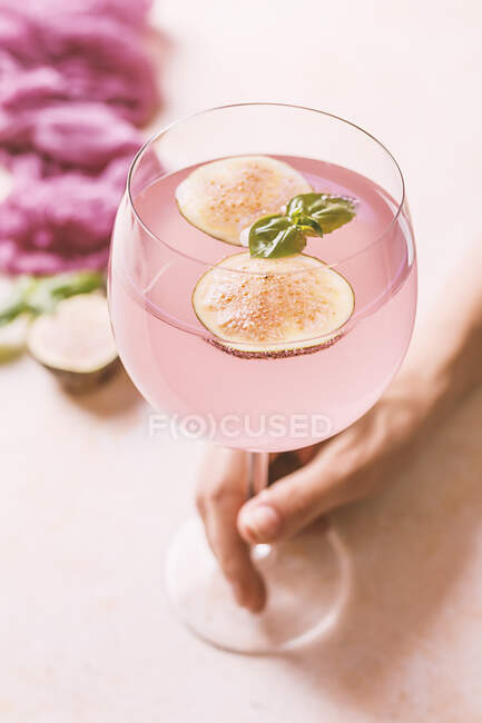 Femme tenant cocktail rose à la figue et au basilic — Photo de stock