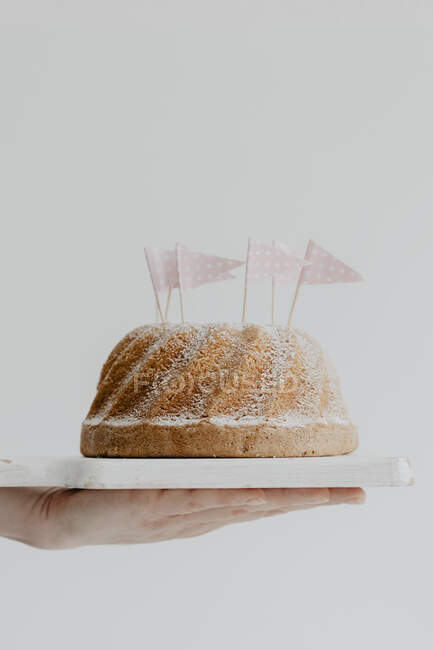 Un gugelhupf decorado con azúcar en polvo y banderas de papel - foto de stock