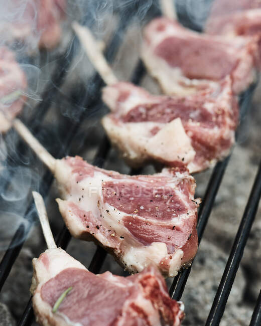 Fresh lamb racks layed on a barbecue to cook — Stock Photo