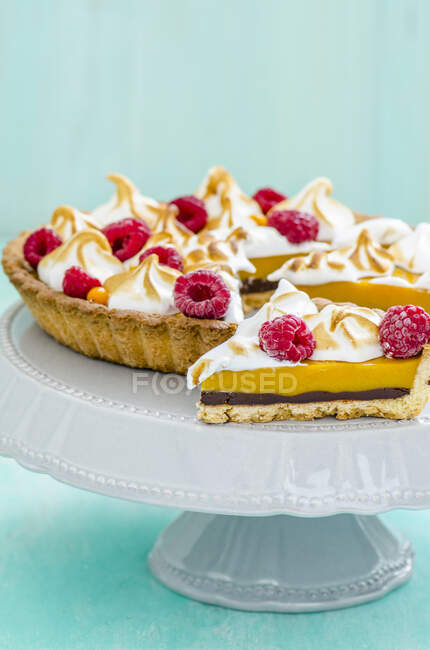 Tart with meringue top and raspberries, pie and slice on stand — Stock Photo