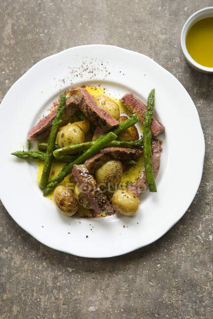 Roast new potatoes and asparagus with seared steak and mustard dressing — Stock Photo