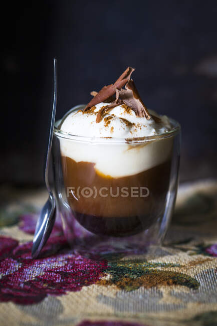 Un vaso de café con crema y chocolate - foto de stock
