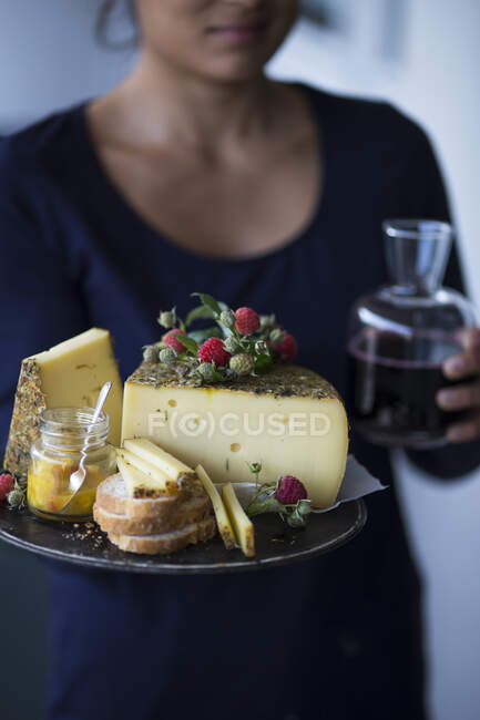 A woman holding a tray of wild herb cheese, bread and chutney — Stock Photo