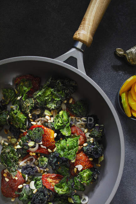 Flower sprouts with tomatoes and pine nuts in a pan — Stock Photo
