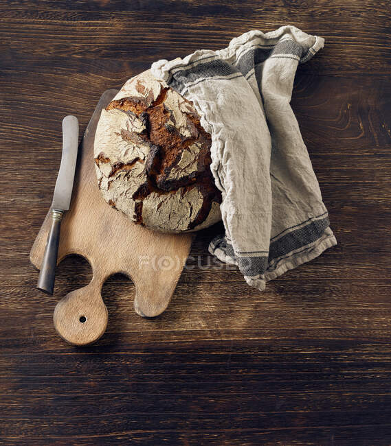Un pain croustillant sur une planche de bois — Photo de stock