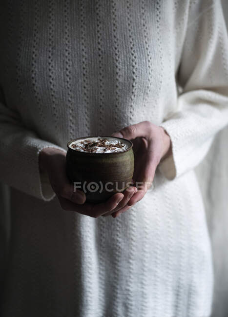 A woman holding a cup of vegan hot chocolate with soy cream — Stock Photo