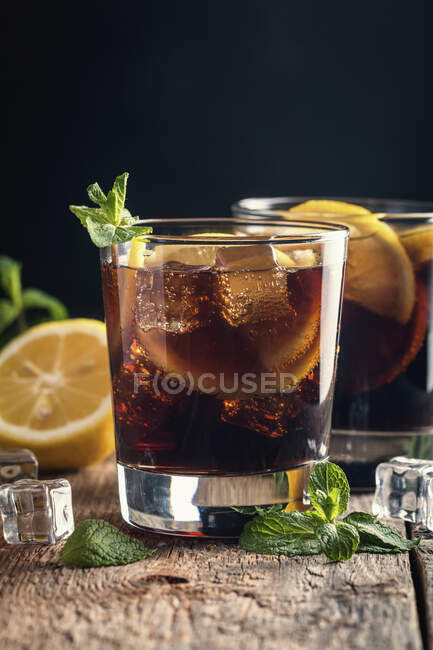 Frisch zubereitete Cuba Libre Cocktails mit braunem Rum, Cola, Minze und Zitrone — Stockfoto
