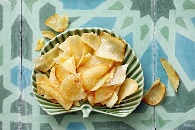 Fresh baked potato chips with cheese and lemon on a blue background. — Stock Photo