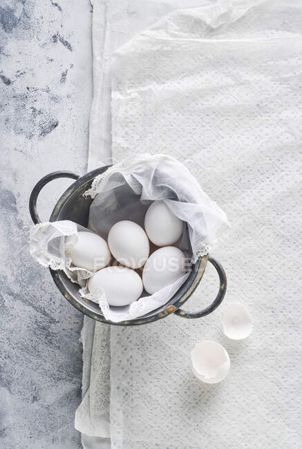 Bodegón de huevos en sartén y cáscaras en tela blanca - foto de stock